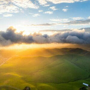 the sun is shining through the clouds over the hills